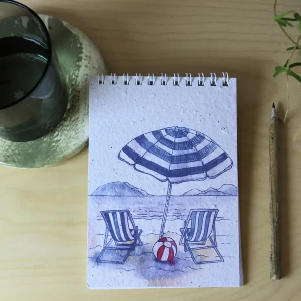 two deck chairs and a striped umbrella on the beach